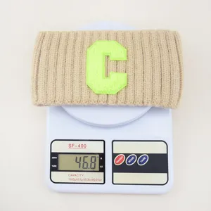 Vista dettagliata della fascia per capelli in maglia larga con patch lettera C verde, lana