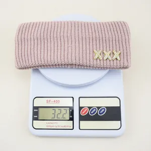 Vista dettagliata della fascia in maglia rosa con ornamenti di croce in strass, peso.