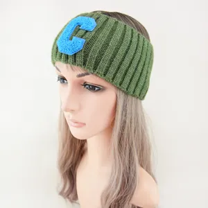 Vista dettagliata della fascia in maglia verde con patch lettera C blu, morbida.