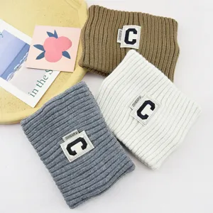 Détail du bandeau en tricot avec texture côtelée douce et écusson lettre C chic.