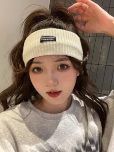 Close-up of knitted headband with letter label, soft texture for comfortable daily wear.