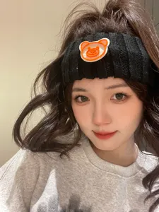 Close-up detail of the black knitted headband featuring a cute orange bear patch design.