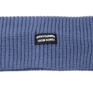 Detailed shot of a blue knitted headband featuring a stylish black woven label design.