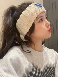 Detailed view of the cute knitted headband with blue bear patch, soft wool texture.
