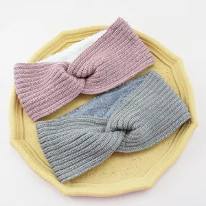 Close-up detail of cozy fleece-lined knitted cross headbands in pink and grey winter accessories.