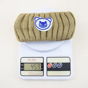 Knit headband detail view, cozy winter hair accessory with cute blue bear embroidery patch.