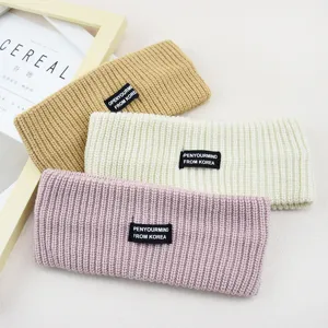 Knitted wide hairband set in khaki, white, and pink. Detailed close-up of winter cozy hair accessories.