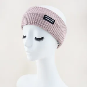 Detailed view of the knitted headband featuring a stylish black woven label. Soft textured fabric.