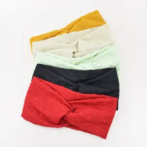Detail view of colorful crinkled fabric cross headbands showing textured layers and color variety.