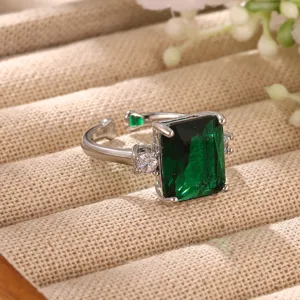 Close-up detail of vintage emerald green zircon open ring with sparkling side stones and gold finish.