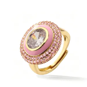 Anello in ottone dorato con zircone centrale ovale, smalto rosa e pietre brillanti incastonate.