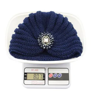Detail view of navy blue knit turban hat with crystal rhinestone brooch ornament.