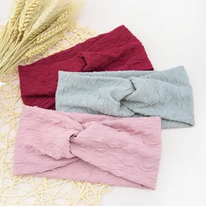 Detail shot of textured cross headbands in pink, grey and wine red, showing fabric details.