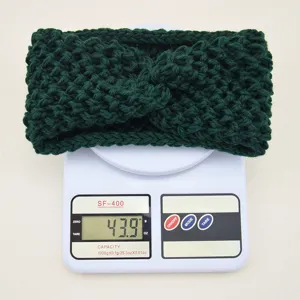 Vue détaillée du bandeau croisé tricoté vert foncé sur une balance numérique de pesée.