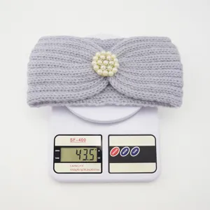Close up of grey knitted headband with pearl rhinestone detail, showing weight on scale.