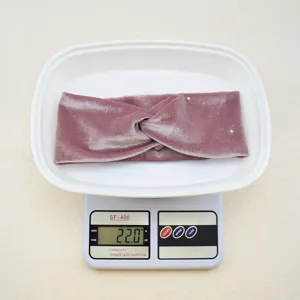 Detail shot of the mauve velvet cross headband, showing soft fabric texture and product weight.