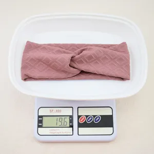 Detailed view of a stylish purple quilted cross headband displayed on a digital scale.