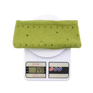 Close-up detail of green knitted headband with distressed holes on weight scale showing 34.9g.