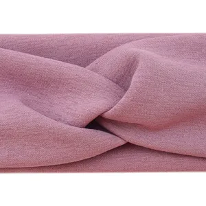Close-up detail of a soft dusty pink knotted fabric headband, stretchy and breathable.