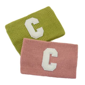Dettaglio fascia in maglia con lana morbida, toppa con lettera C bianca e design a doppio strato.
