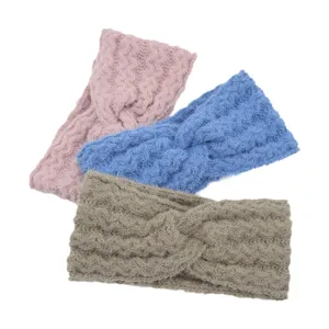 Detailed shot of three colorful knitted cross headbands in pink, blue, and khaki.