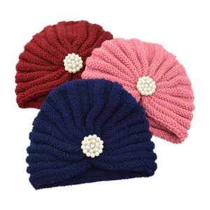 Knitted turban hats detail view featuring elegant pearl flower decorations in three colors.