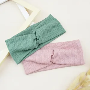Vue détaillée de bandeaux croisés en tricot élastique vert et rose avec texture losange.