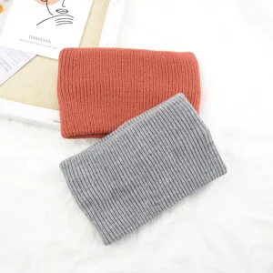 Close up detail of soft knitted winter headbands in orange and grey colors, cozy ribbed texture.