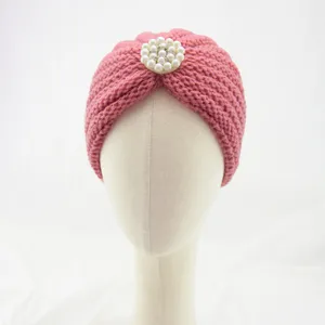 Pink knitted turban hat for women, stylish winter head wrap with elegant pearl rhinestone brooch.