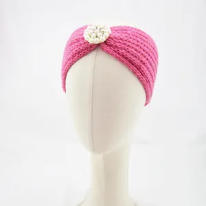 Detail of the pink knitted headband featuring an elegant pearl and rhinestone flower decoration.