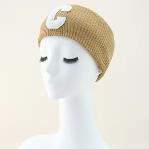 Fascia per capelli in maglia beige con toppa lettera C bianca, comodo accessorio donna.