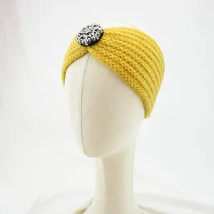 Close-up of a yellow knitted winter headband with a sparkling crystal flower ornament.