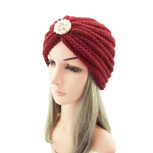 Close-up detail of the dark red knitted turban hat showing intricate rib texture and pearl brooch.