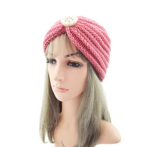 Close-up of pink knitted turban hat detail, featuring elegant pearl rhinestone embellishment.