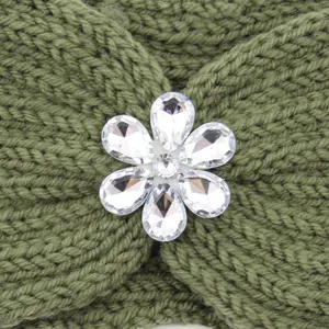 Close-up view of a green knit headband featuring a sparkling rhinestone flower decoration.