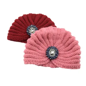 Detailed view of women knitted crystal turban hats in wine red and pink with sparkling jewels.