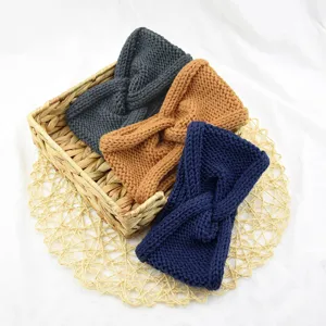 Detail shot of three knitted twist headbands in woven basket, soft winter warm hair accessories.