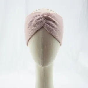 Close-up of pink knitted headband, soft textured cross design for warm autumn winter wear.