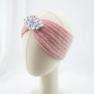 Close-up of pink knitted headband with crystal rhinestone flower detail for stylish warmth.