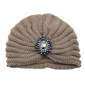 Detailed view of brown knitted turban hat featuring a sparkling dark blue crystal brooch centerpiece.
