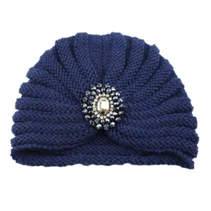 Close-up detail of the dark blue knitted turban hat with crystal brooch decoration.