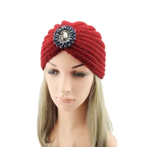 Red knitted turban hat with large crystal rhinestone brooch for stylish winter wear.