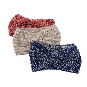 Closeup view of handmade knitted cross headband with gold thread details, cozy winter hair accessory.