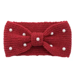 Detailed close-up of a red knitted wool headband adorned with elegant white faux pearls.