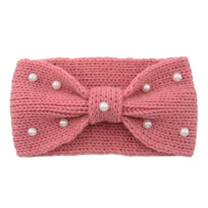 Close-up detail view of the pink knitted wool headband featuring elegant white pearls and bow.