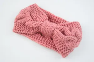 Gedetailleerde close-up van de roze kabeltje gebreide strik hoofdband met zachte woltextuur.