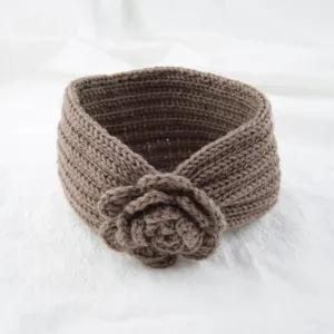 Brown knitted wool headband with crochet flower detail, close-up view of winter warm hair accessory.