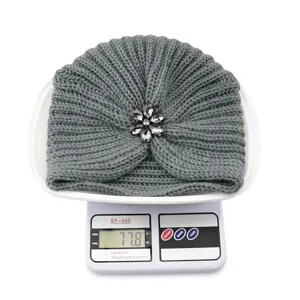 Detailansicht der grauen Strick-Turbanmütze mit Kristall-Strassblumenbrosche, Gewicht.