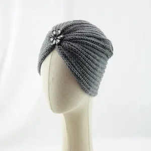 Nahaufnahme einer grauen Strickturbanmütze mit Kristallblumen-Dekor für den Winter.