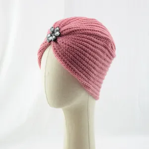 Nahaufnahme der rosa Strickturbanmuetze mit glitzerndem Kristallblumenbroschen-Detail.